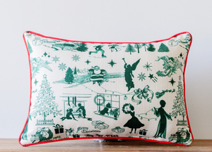 White pillow with various Christmas images in a green color tone. Images include: an angel; Santa Claus; Christmas tree; fireplace with stockings, etc. Red trim around pillow.