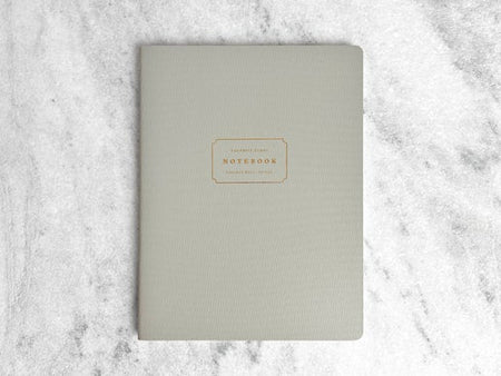 Notebook with gray cover with gold text box in center with gold foil text saying, “Favorite Story Notebook”.
