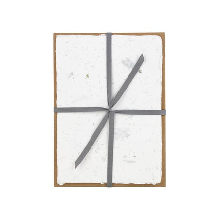 Off white speckled blue paper with a torn edge wrapped and tied with a single gray ribbon.