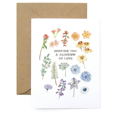 White card with images of several colored flowers with black text saying, “Sending You a Rainbow of Love”. A brown kraft envelope is included.