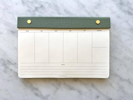 Off white calendar with green leather binding across the top attached with brass screws.