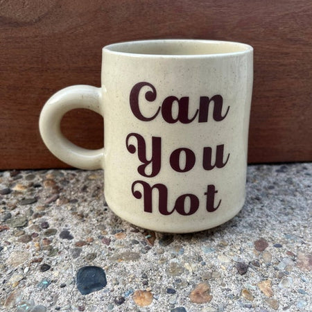 Ivory mug with tiny brown speckles and brown text saying, “Can You Not”.