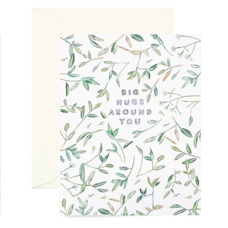 White card with images of green leaves scattered across card. Blue text in center saying, “Big Hugs Around You.” A white envelope is included.