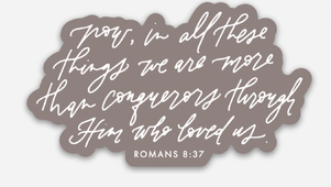 Gray sticker with white script text, “Now, in all these things we are more than conquerors through Him who loved us. Romans 8:37”.