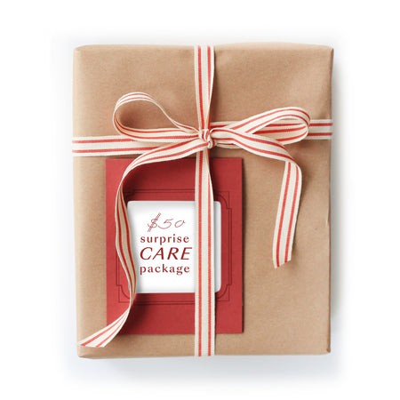 Rectangle package wrapped in brown kraft paper with a red and white striped ribbon and red card with red text saying, “$50 Surprise Care Package”.