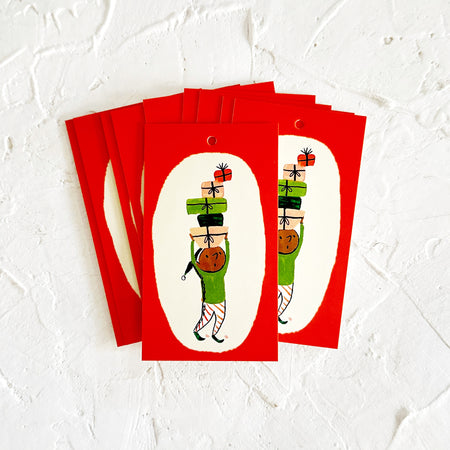 Rectangular red tags with white oval inlay with image of an elf wearing a green outfit carrying several presents on his head.