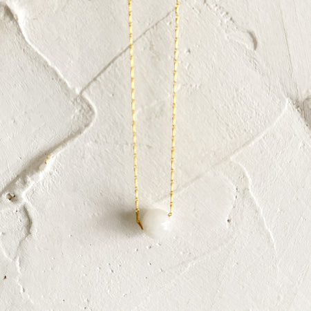 Gold necklace with a rope chain with a moonstone gemstone in center. 