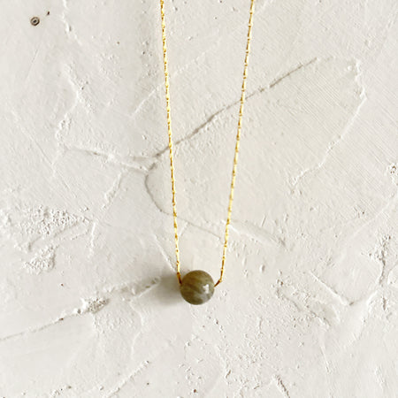 Gold necklace with a rope chain with a labradorite gemstone in center. 