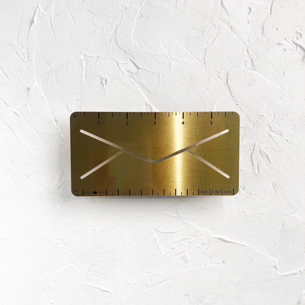 Rectangle gold metallic ruler designed to look like a mailing envelope. 