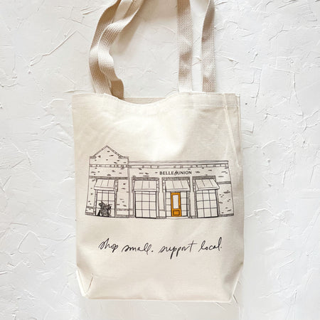 Ivory tote bag with black text saying, “Shop Small, Support Local”. Image of the Belle & Union store building.