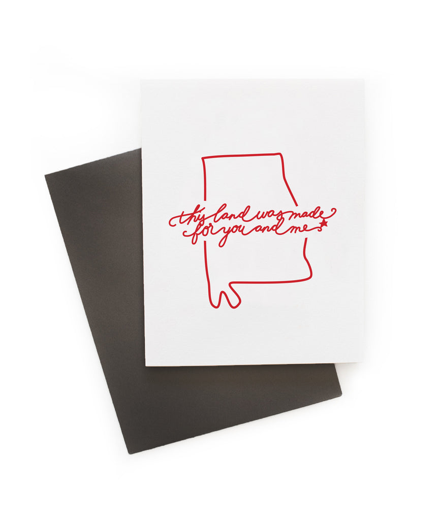 White card with red text saying, “This Land is Made for You and Me”. Red outline image of the state of Alabama. A gray envelope is included.