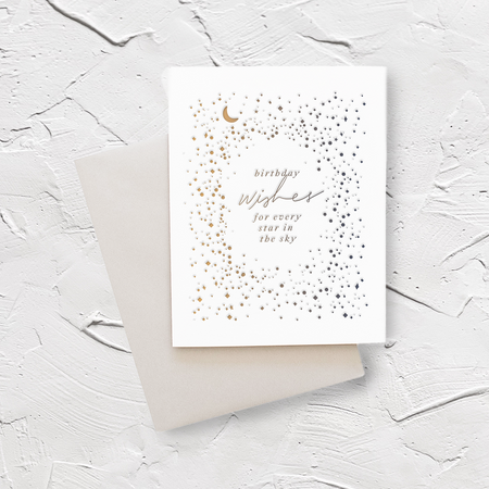 White card with silver and gold text saying, “Best Wishes for Every Star in the Sky”. Images of small embossed silver and gold stars scattered across card with gold moon. A gray envelope is included.