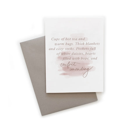 White card with tan text saying, “Cups of hot tea and warm hugs. Thick blankets and cozy socks. Pockets full of white daisies, hearts filled with hope, and comfort unending”. Images of mauve and gray blended paint brushstrokes through center of card. A gray envelope is included.