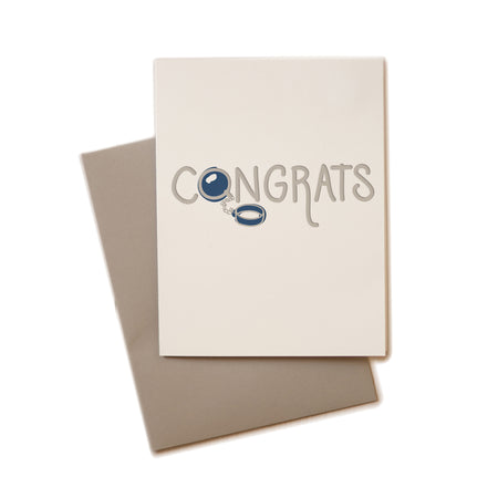 Ivory card with gray text saying, “Congrats”. Images of a blue ball and chain. A gray envelope is included.