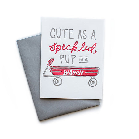 White card with gray and red text saying, “Cute as a Speckled Pup in a Wagon”. Image of a red chlid’s wagon in center of card. A gray envelope is included.