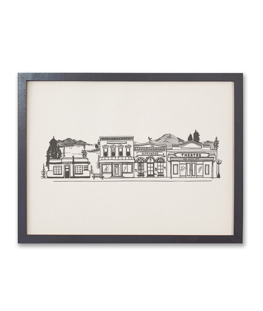 Print with ivory background and black ink. Images of a mountain town with mountains; evergreen trees; town buildings such as coffee shop, hardware store, bank and theatre.