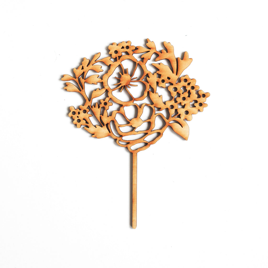 Wooden cake topper cutout in the shape of a floral bouquet.