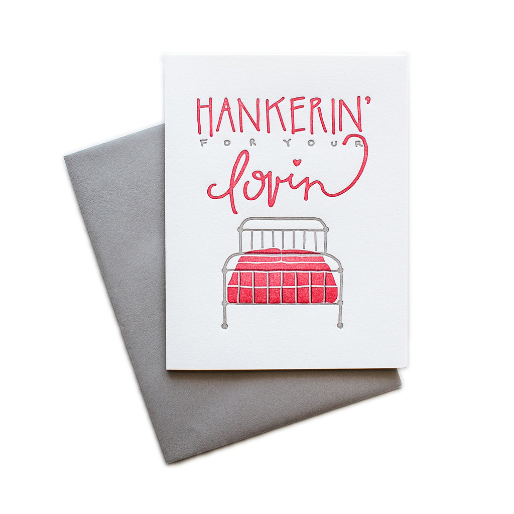 White card with gray and red text saying, “Hankerin For Your Lovin”. Image of a silver metal framed bed with red mattress. A gray envelope is included.