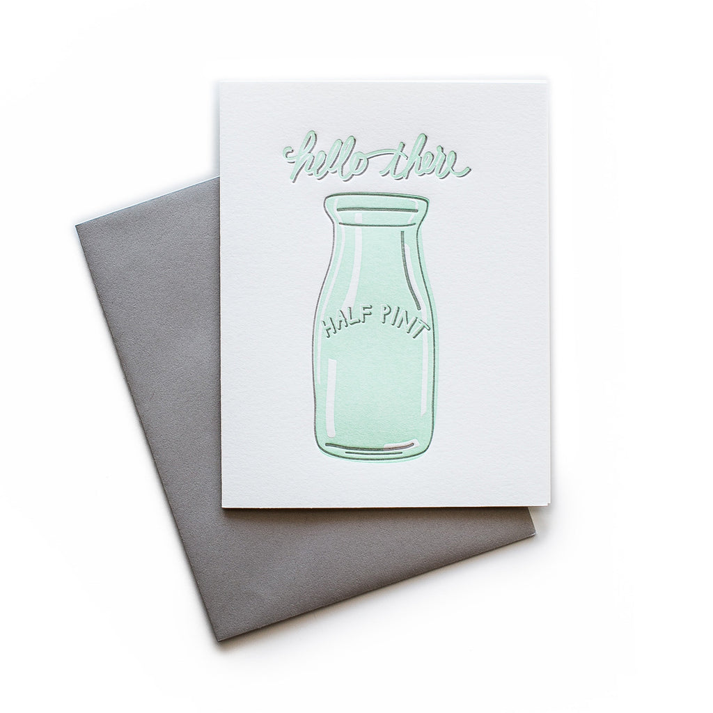 White card with teal text saying, “Hello There Half Pint”. Image of a half pint glass bottle in center of card. A gray envelope is included.