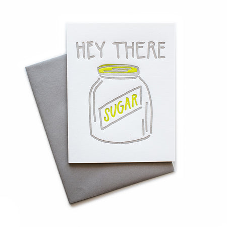 White card with gray and yellow text saying, “Hey There Sugar”. Image of a jar of sugar in center of card. A gray envelope is included.