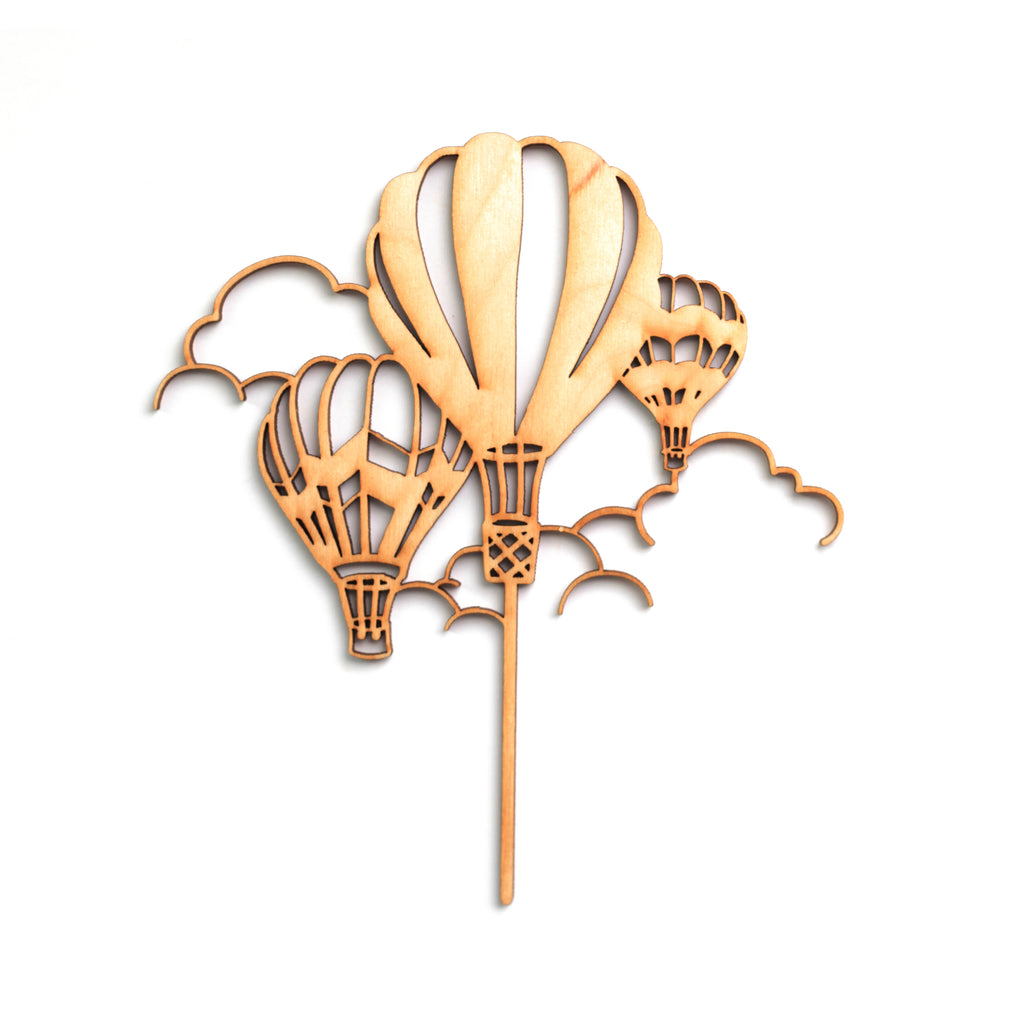 Wooden cake topper cut into the shape of three hot air balloons with clouds.