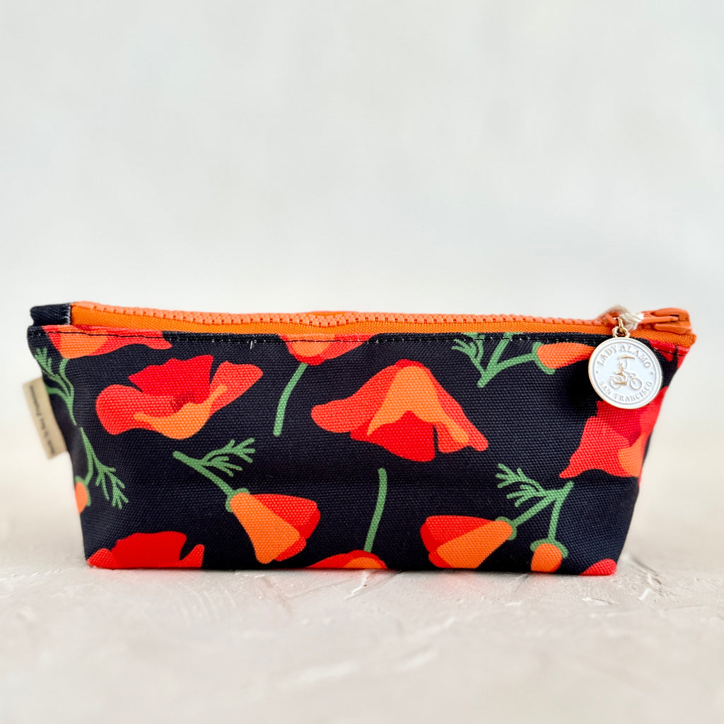 Rectangular travel pouch with black background and red poppy floral design. Orange zipper across the top.