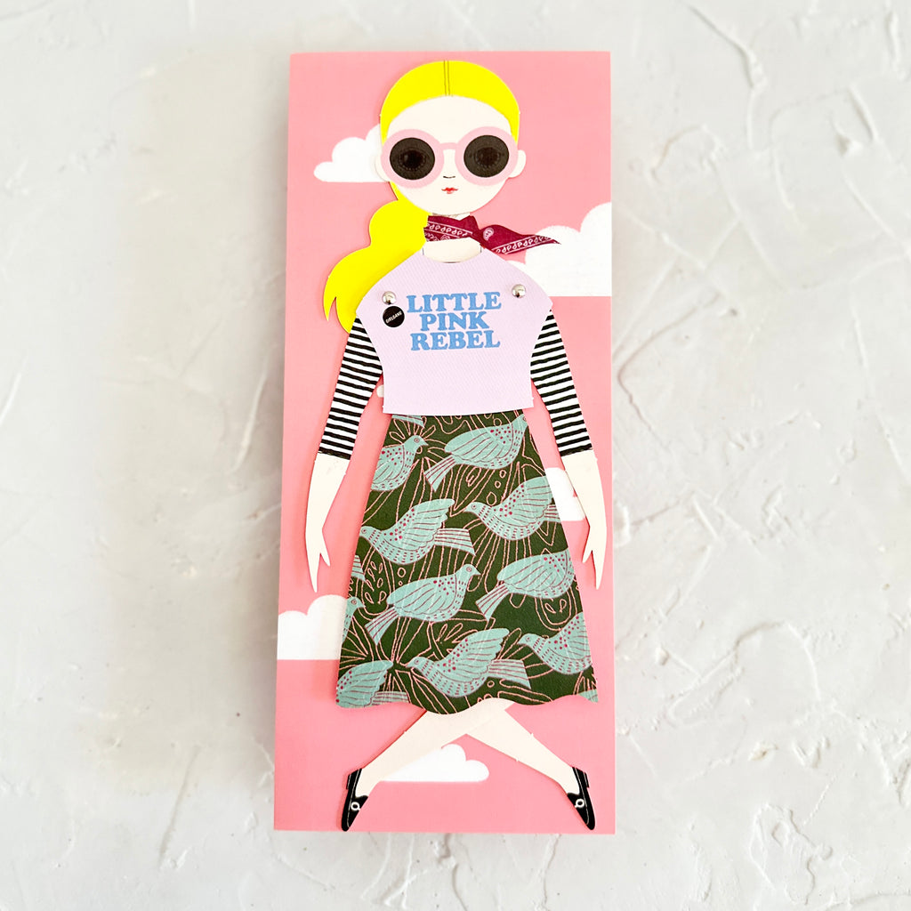 Pink background card with image of a girl wearing a pink shirt saying, “Little Pink Rebel”; a green skirt with birds on it; and a red scarf around her neck.