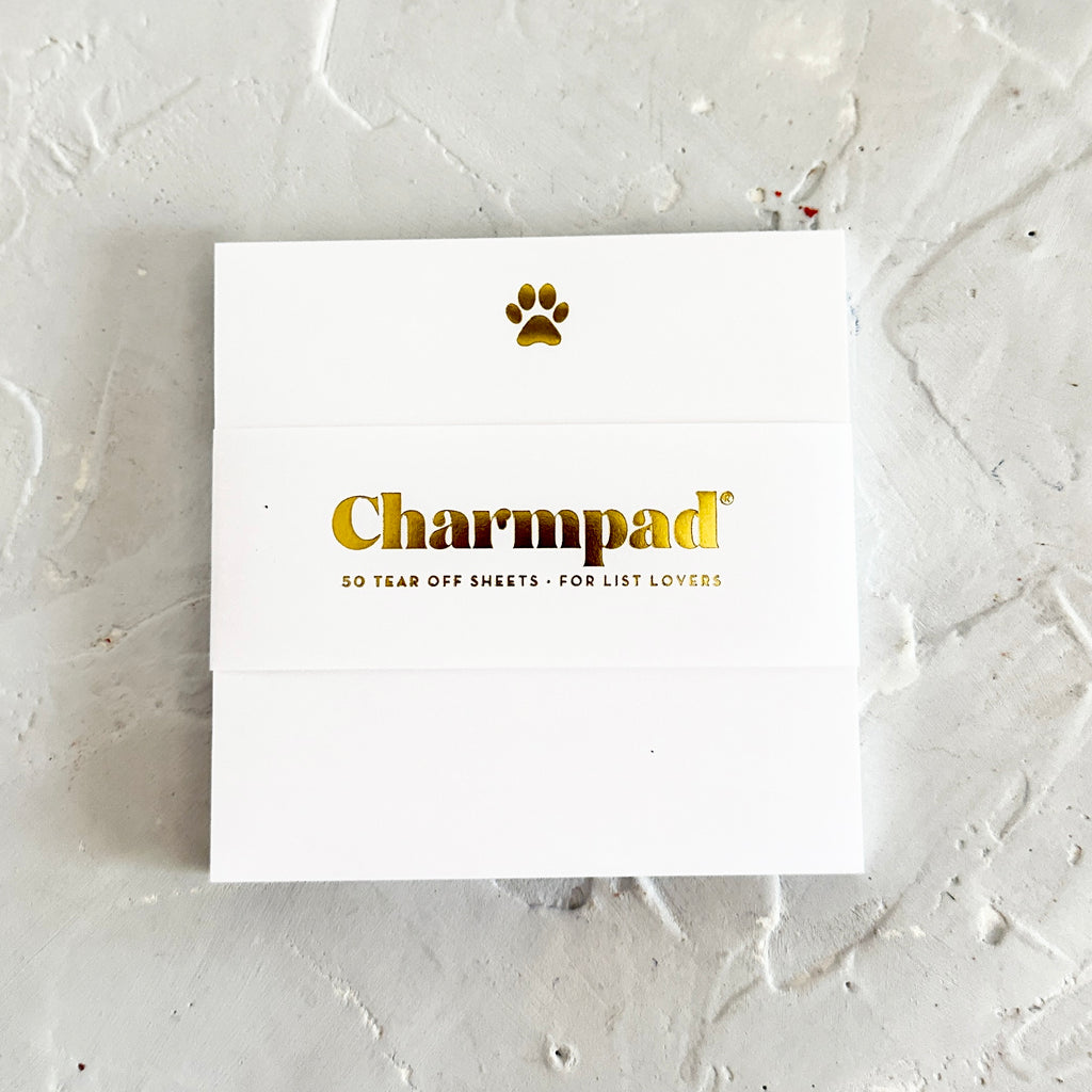 White square notepad with gold foil dog paw in top center.