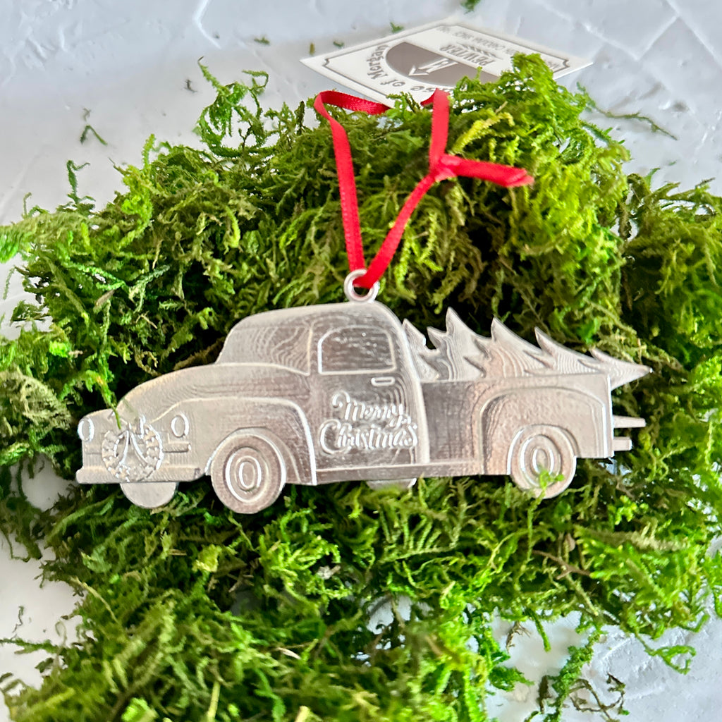 Silver pewter ornament in the image of a country pick up truck with a Christmas tree in the back.