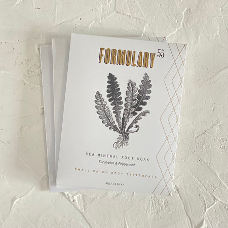 White packet with gold and black text saying, “Formulary 55 Sea Mineral Foot Soak Eucalyptus & Peppermint”. Images of eucalyptus leaves and peppermint sprigs. Angled geometric design going down right side of package.