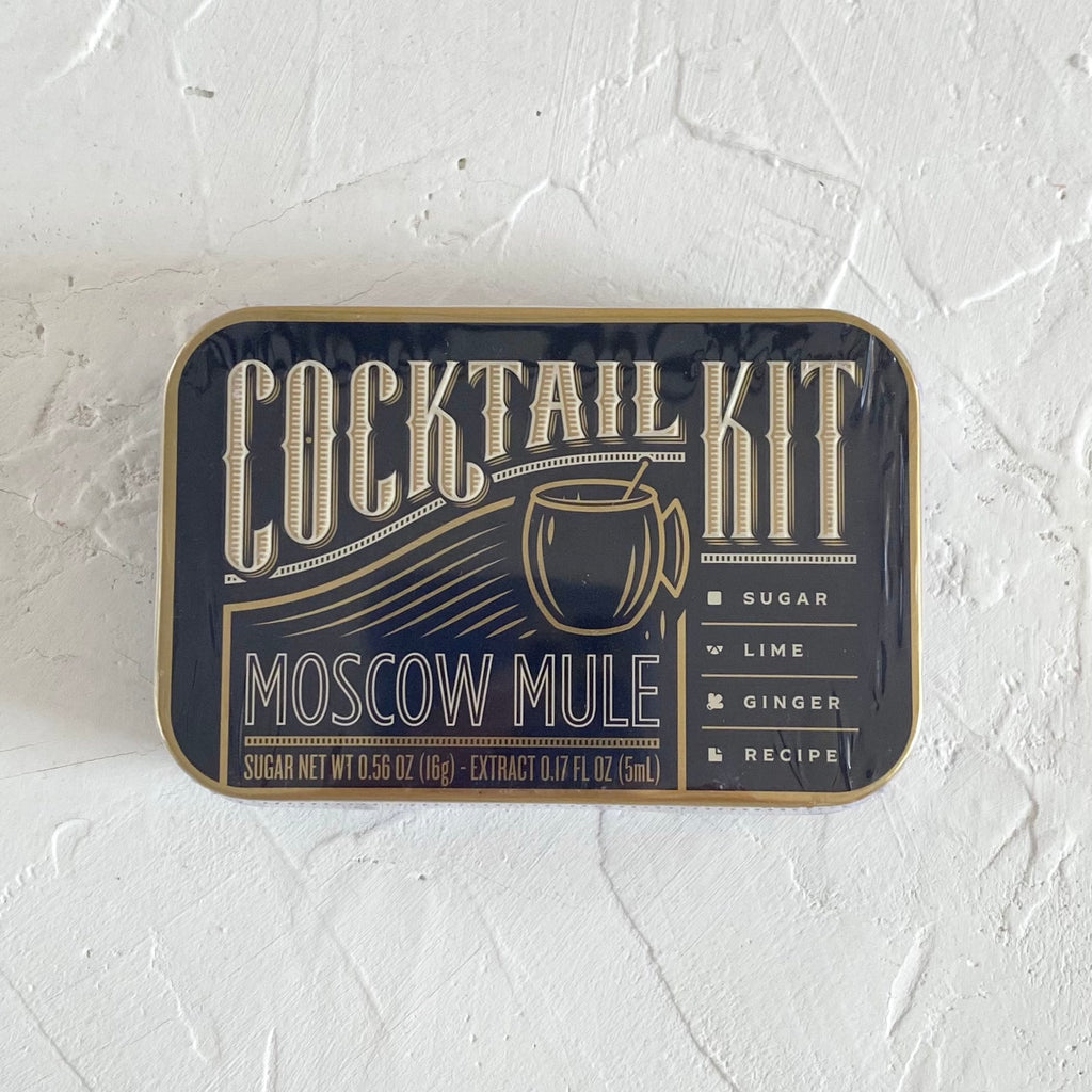 Black rectangle tin with gold and silver accent text saying, “Cocktail Kit Moscow Mule”. Image of a gold cocktail glass.