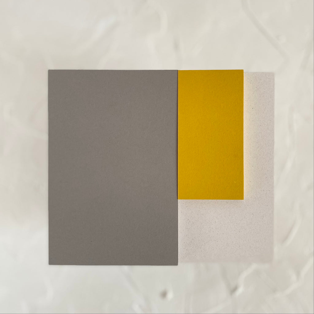 Rectangle note pads with gray, mustard yellow and ivory colored covers.