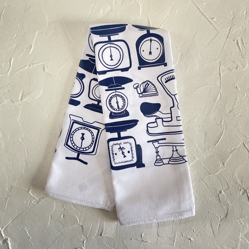 White tea towel with images of vintage scales in blue ink.
