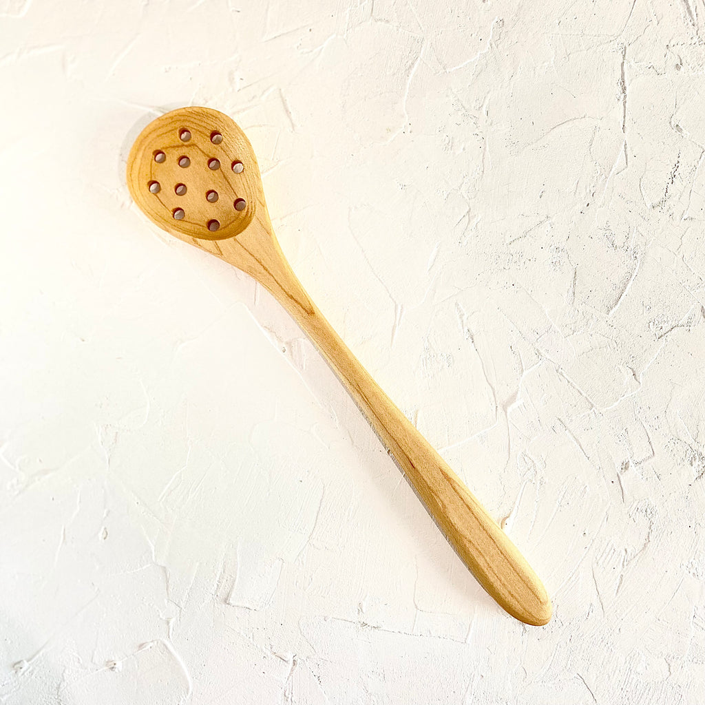 Hand carved wooden spoon with holes. 