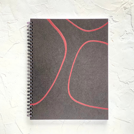 Black cover with red swirls. Silver metal coil binding on left side.