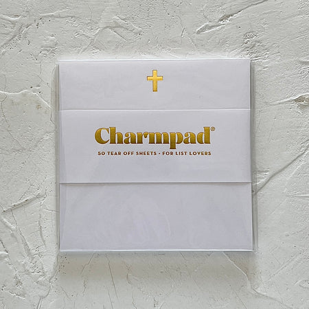 White square notepad with gold foil cross in top center.