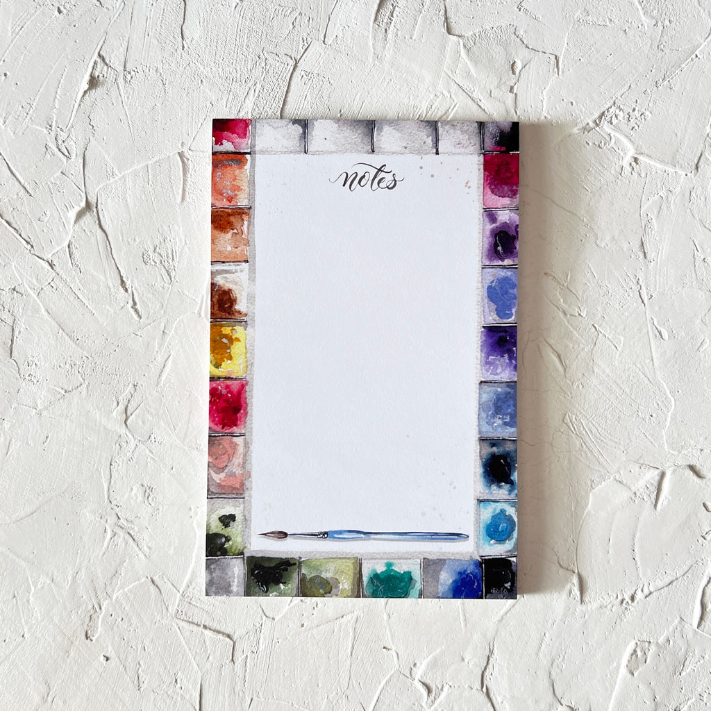 White notepad with black text saying, “Notes”. Images of colors from a paint palette around the edge.