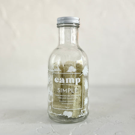 Glass jar with silver lid and white text saying, “Camp Simple”. Mint green colored sugar cubes.