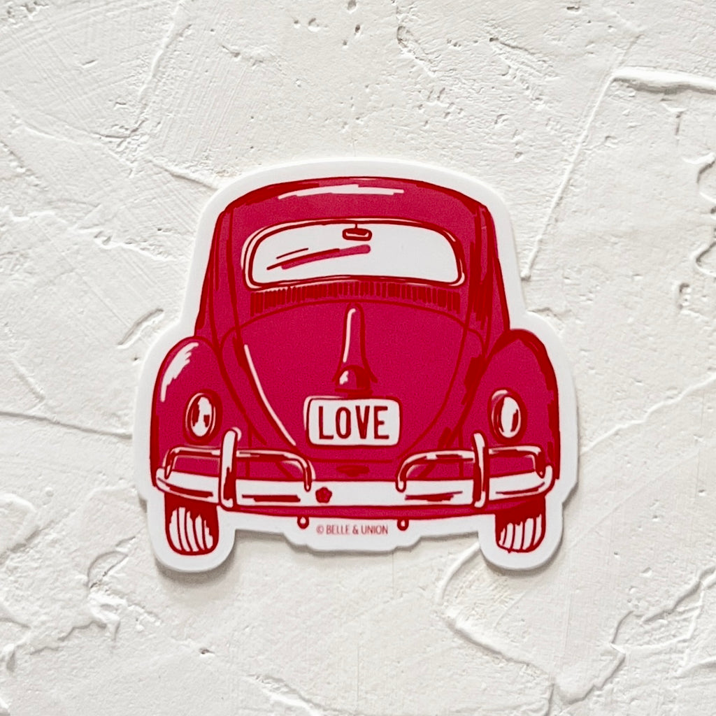 Sticker in the image of a red vintage beetle bug car with “LOVE” written on the back license plate.