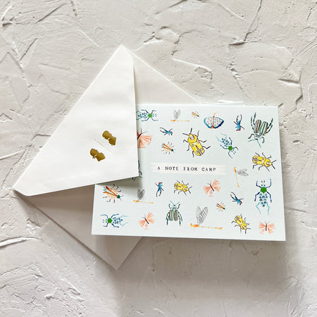 Box set of white notecards with black text saying, “A Note from Camp”. Images of different varieties of bugs and insects. Matching white envelopes included.