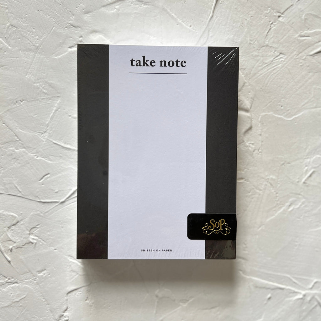 White notepad with black side borders and black text saying, 