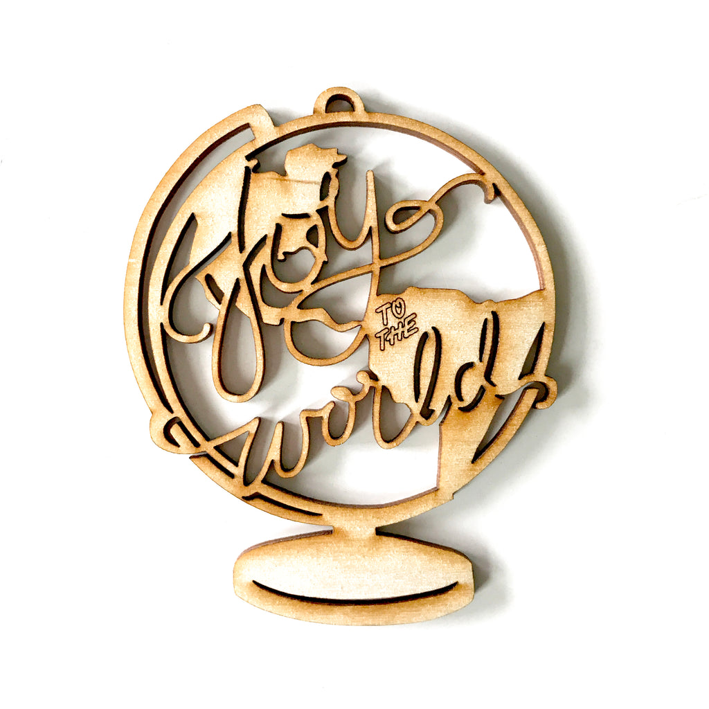 Wooden die cut with image of a globe and text saying, “Joy to the World”.