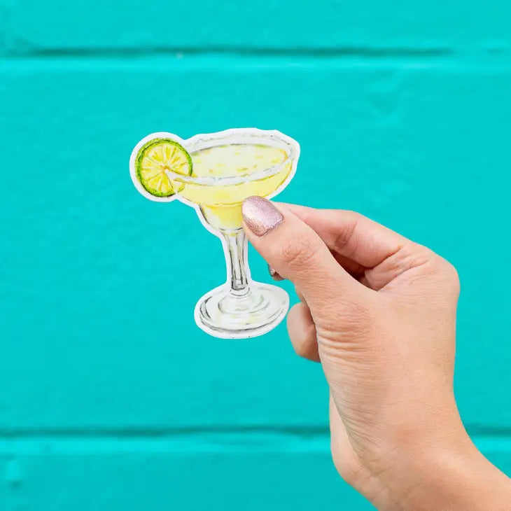 Sticker with an image of a classic margarita with a white sugar rim, a lime slice and ice cubes.