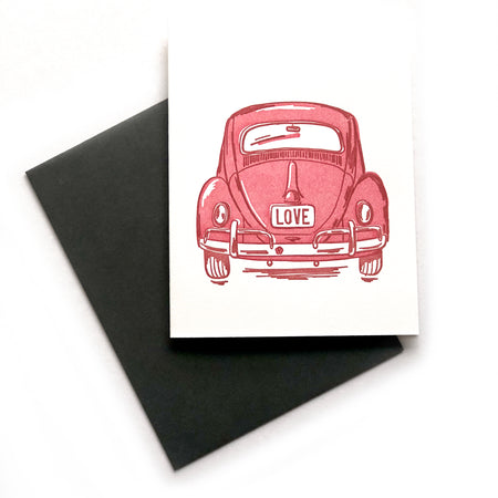White card with image of a red vintage beetle bug car with “LOVE” written on the back license plate. A dark gray envelope is included.