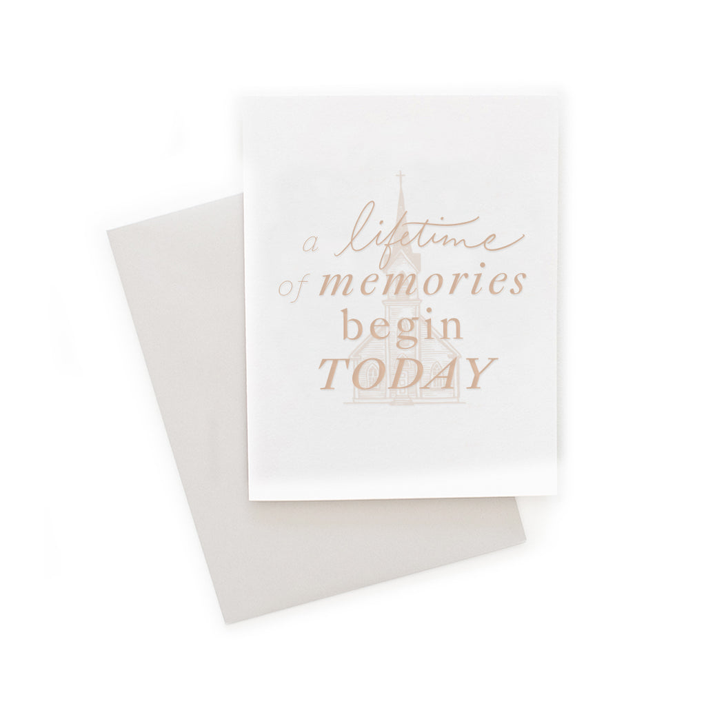 White card with blush pink text saying, “A Lifetime of Memories Begin Today”. Image of a country wedding chapel. A gray envelope is included.