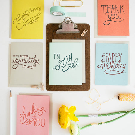 Pack of cards in pink, orange, ivory, light blue, yellow and orange with various colored text saying, “Congratulations”; “Thank You”; “With Deepest Sympathy”; “I’m Sorry”; Happy Birthday”; and “Thinking of You”. Gray envelope is included.