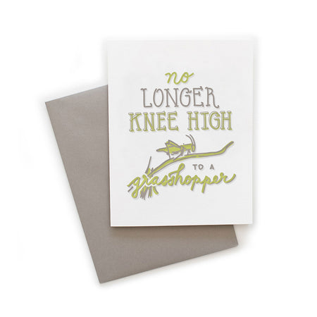 White card with gray and yellow text saying, “No Longer Knee High to a Grasshopper”. Images of a grasshopper sitting on a branch. A gray envelope is included.