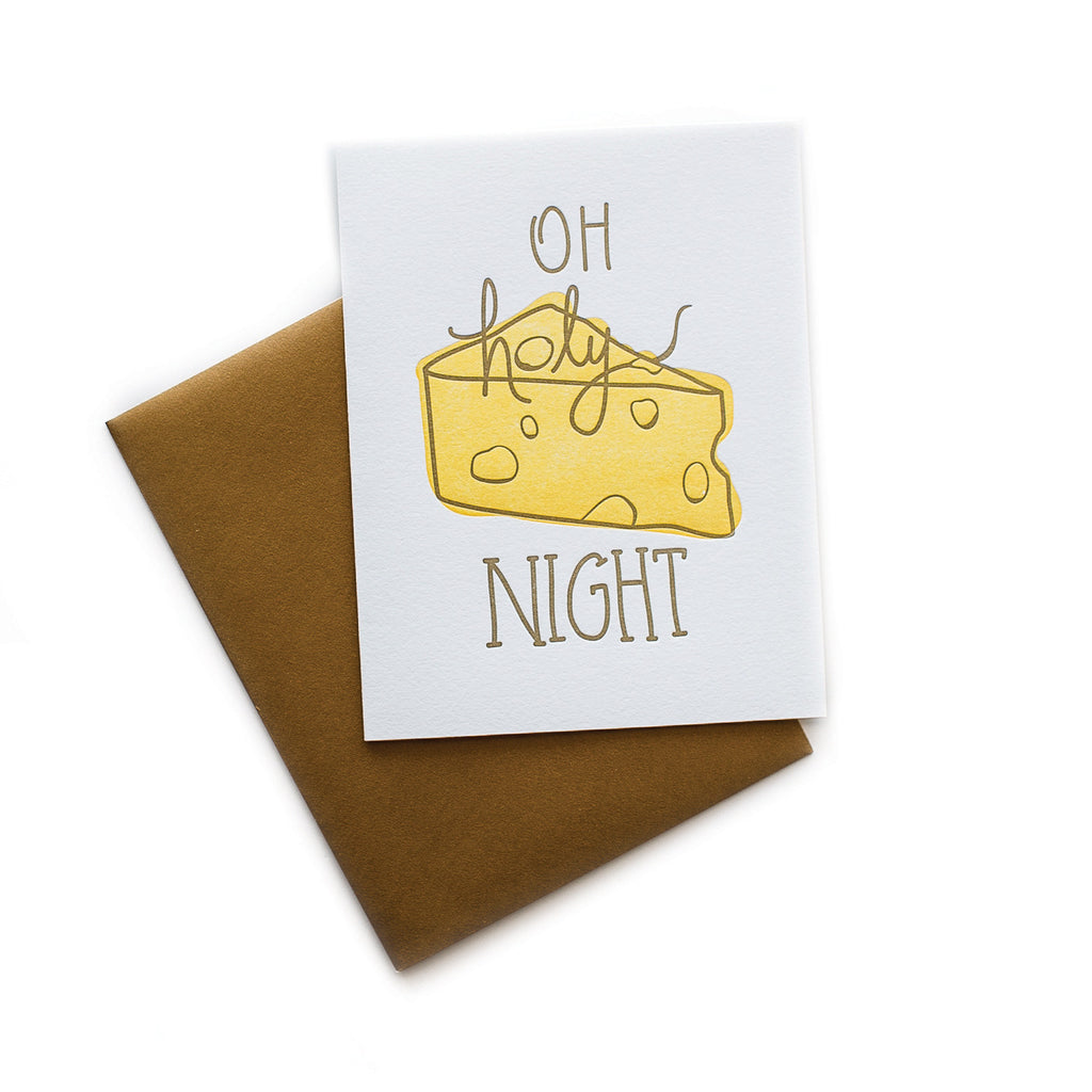 White card with brown text saying, “Oh Holy Night”. Image of a wedge of yellow Swiss cheese. A brown envelope is included.