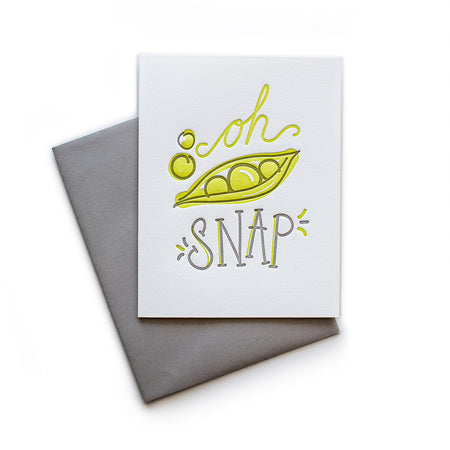White card with gray and yellow text saying, “Oh Snap”. Image of a snap pea pod. A gray envelope is included.