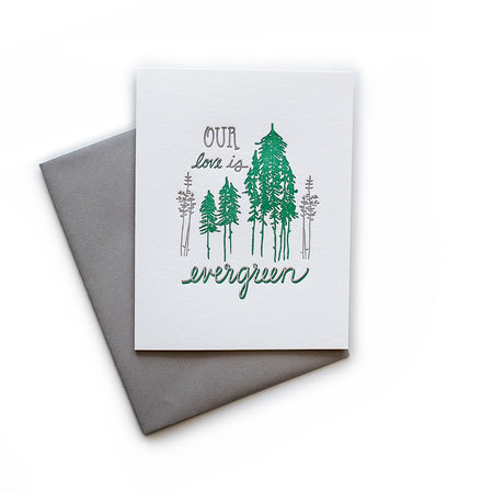 White card with gray and green text saying, “Our Love is Evergreen”. Images of gray and green evergreen trees. A gray envelope is included.